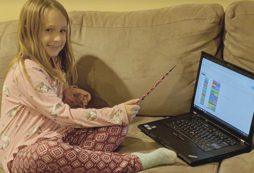 Little girl with a magic wand, waving it in front of a computer.